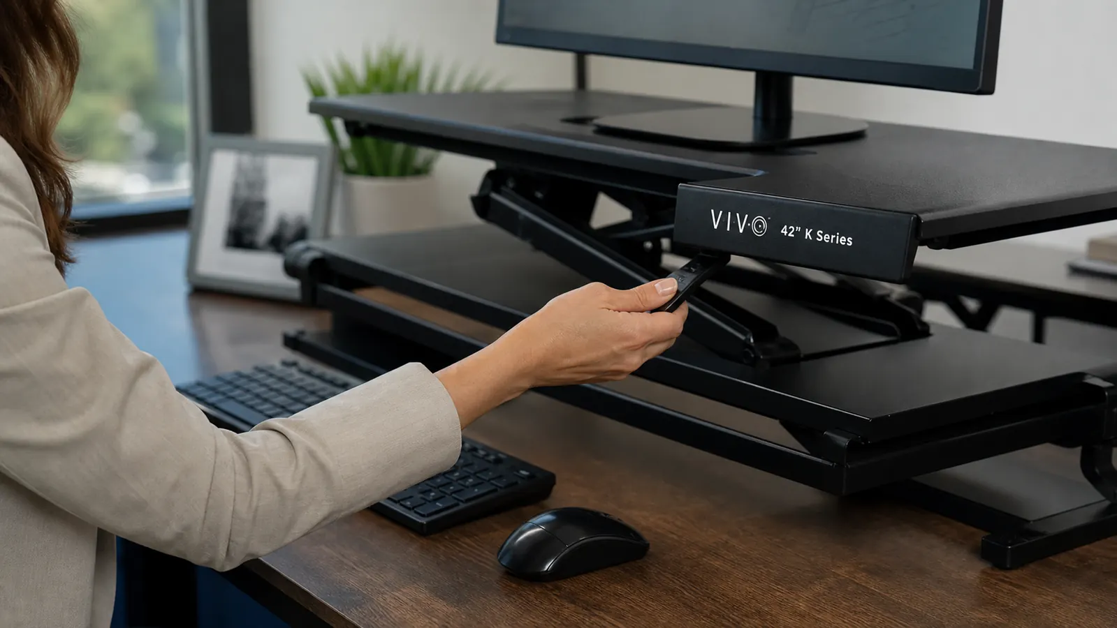 Close-up of hands adjusting the height-release lever on a standing desk converter